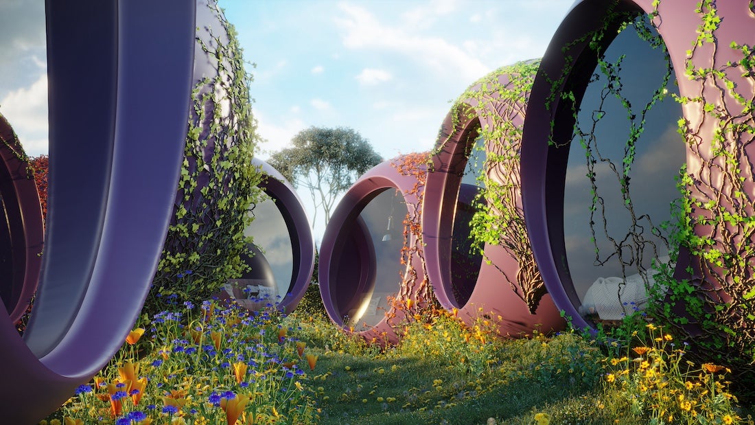 A digital rendering of a futuristic architectural landscape featuring several interconnected, rounded, purple and pink structures. The structures have large, circular openings with reflective glass, resembling windows or doorways. Green vines climb up the sides of these structures. The scene is set in a lush meadow with a variety of colorful wildflowers in the foreground, including yellow and blue blossoms. A tree is visible in the background against a blue sky with scattered clouds. The overall aesthetic is whimsical and organic, blending futuristic design with natural elements.