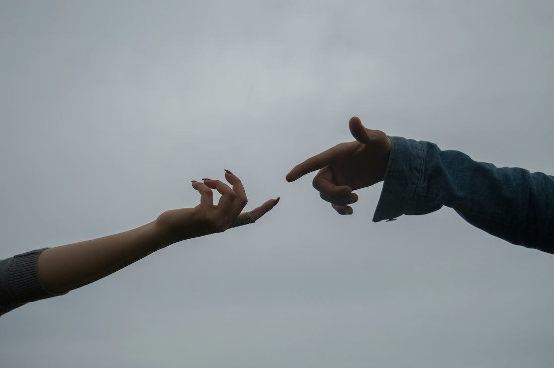 two hands trying to meet each other in the middle of the image, though their fingers are limp, implying that they're not trying very hard.