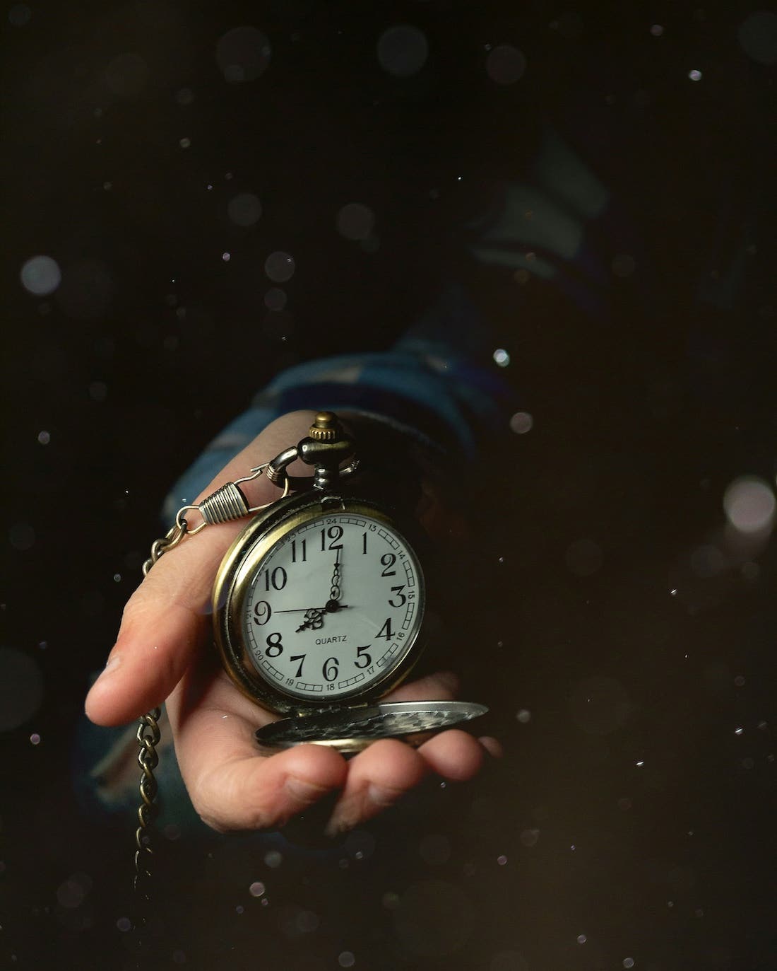 a close up of a hand holding an open pocket watch