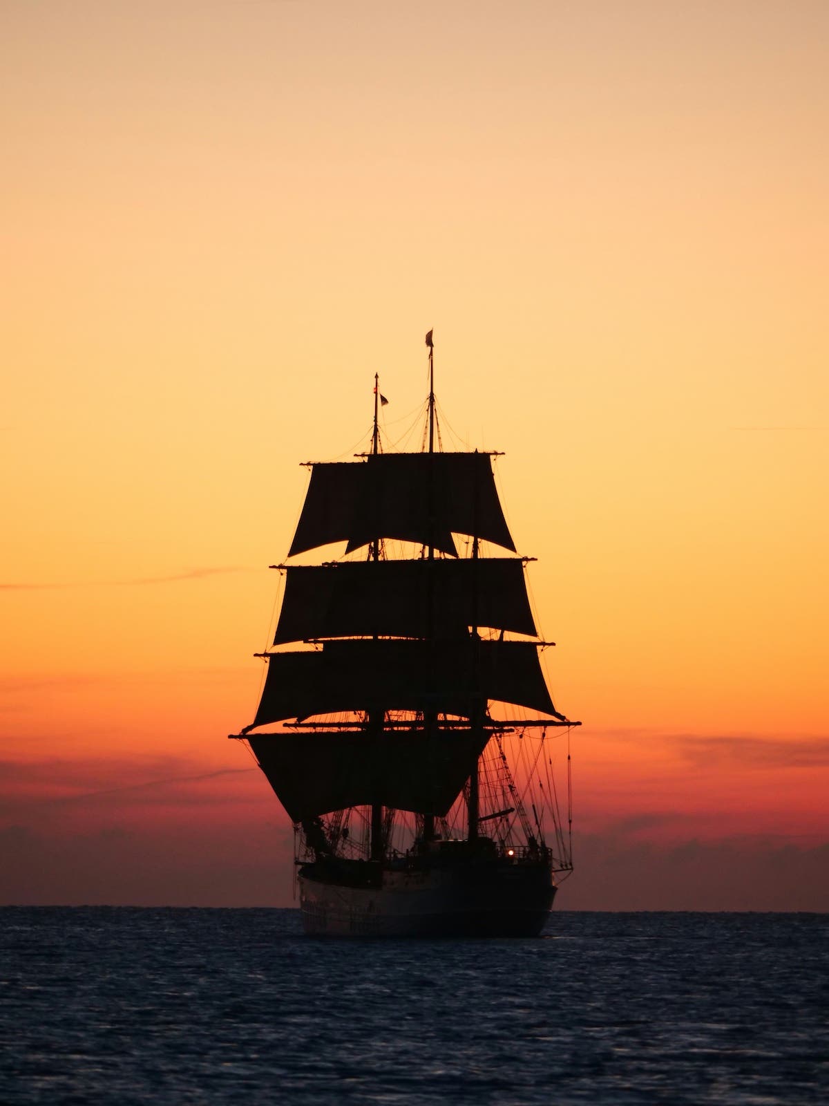 the silhouette of a huge ship against the sunset