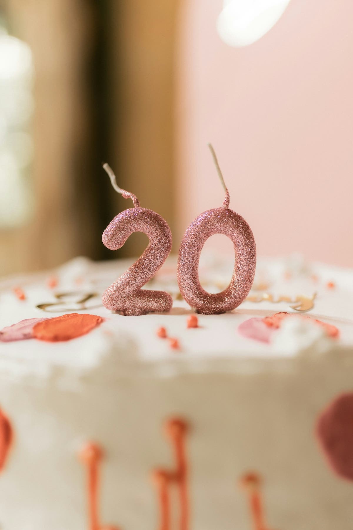 Close up of pink birthday candles spelling out 20 on top of a cake
